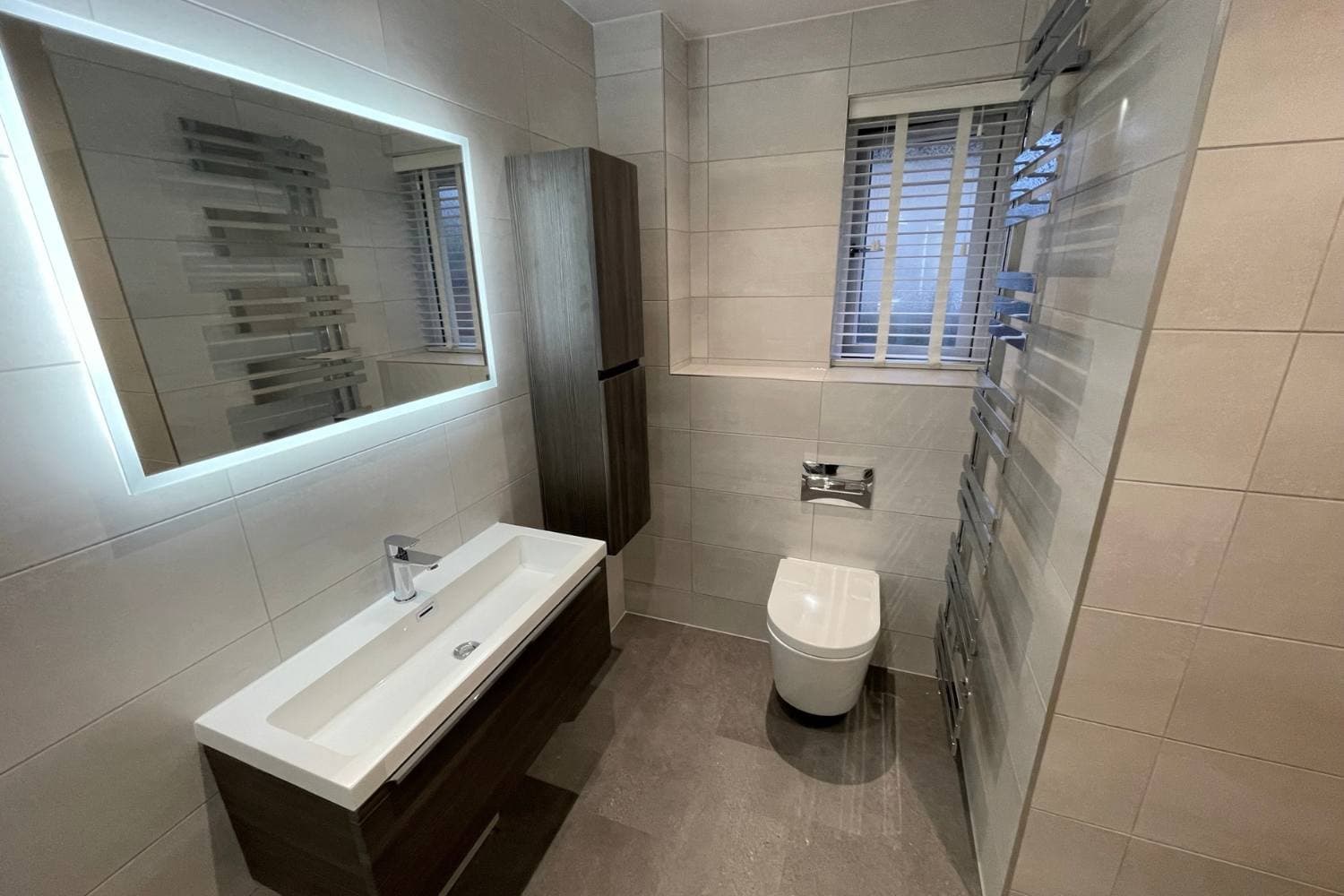 Tiled bathroom with illuminated mirror and vanity from Alpha Renovations’ website